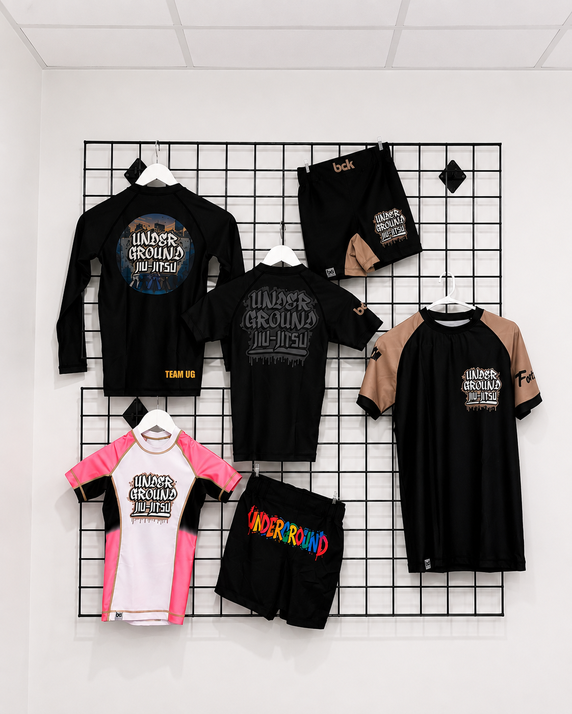 Underground Jiu-Jitsu no-gi rash guards and grappling shorts on a display grid